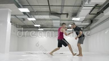 在一间白色的房间里，两个男摔跤手在扔<strong>垫子</strong>。 抓住一个抓斗把自己扔出去