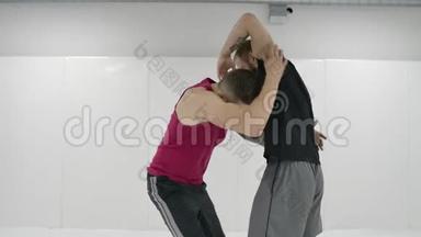希腊罗马摔跤手在一个有<strong>垫子</strong>的白色房间里。 练习自卫技巧。 投掷和疼痛