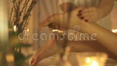 年轻女子在美容院做脚部按摩，关门。 蜡烛背景