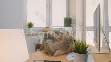 疲惫的女人在工作场所醒来。 疲惫的金发女办公室工作人员穿着优雅的西装，<strong>放</strong>松地躺在<strong>桌子上</strong>，然后躺在<strong>桌子上</strong>