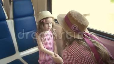 可爱的小女孩和她的妈妈一起旅行-牵着手，在靠近窗户的火车上交谈
