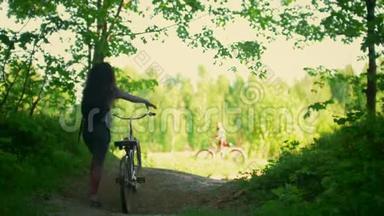 女孩骑自行车的人在森林里的空地上遇见她的朋友，阳光明媚的夏日