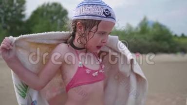 海滩上的一个女孩洗澡后用毛巾擦拭身体。 暑假，海边休息..