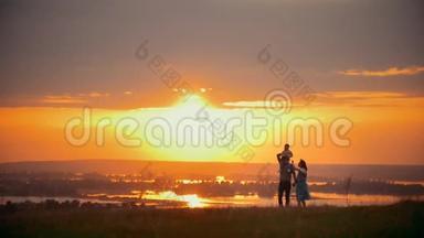 一家人迎着夏日的夕阳散步，爸爸妈妈牵着手，儿子坐在肩上