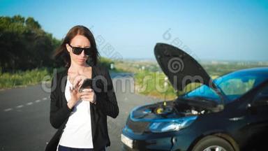路上一辆破车附近的女人正在呼救。 年轻担心的女孩正在用电话解释