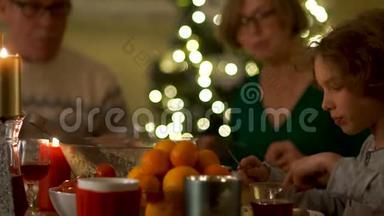 祖父、祖母、儿子和孙子坐在圣诞桌旁吃饭。 感恩，幸福的家庭.. 新年快乐