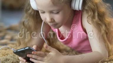 小女孩躺在地毯上，用手机听耳机听音乐