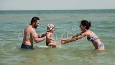 快乐的父母和孩子在海里玩耍。 父亲在旋转，手里拿着儿子，母亲在<strong>努力</strong>