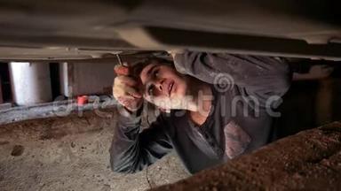 汽车底下的年轻人在车库坑里修理汽车