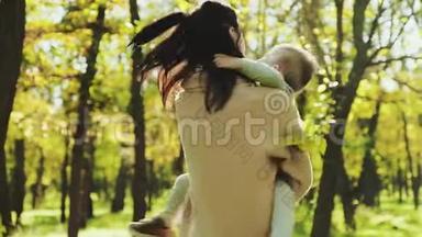 在秋天的公园里，年轻的母亲和她的儿子在<strong>怀里</strong>旋转