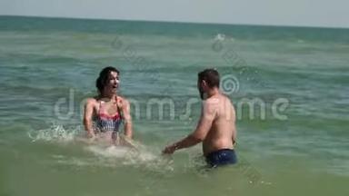 一对夫妇在海水中玩耍。 他们互相残杀。 然后年轻人放弃，掉进水里