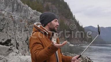 大胡子的游客正在一条<strong>山河</strong>的河岸上用手机播放<strong>视频</strong>。 慢动作