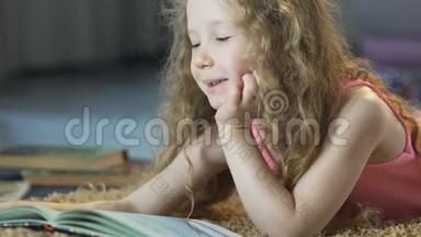 可爱的卷发女孩躺在地毯上，大声朗读童话故事，快乐的童年