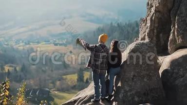 年轻的旅游夫妇相爱，站在岩石上，欣赏美丽的景色。 拜访著名游客的男人和女人