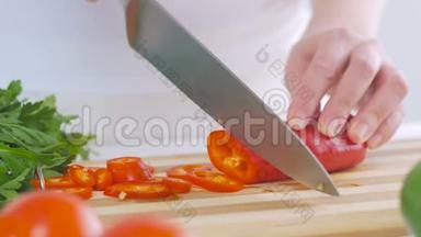一个女人在厨房里切红辣椒，准备一份美味的新鲜蔬菜沙拉作<strong>为</strong>午餐