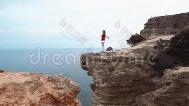 女人站<strong>在</strong>海边的<strong>悬崖上</strong>沉思。 <strong>在悬崖上</strong>做瑜伽。