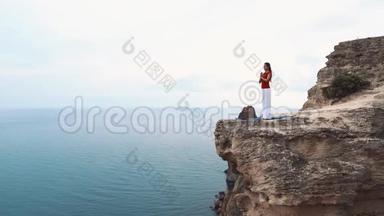 女人站<strong>在</strong>海边的<strong>悬崖上</strong>沉思。 <strong>在悬崖上</strong>做瑜伽。