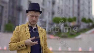 魔术师戴着帽子，穿着黄色夹克，手里拿着扑克牌