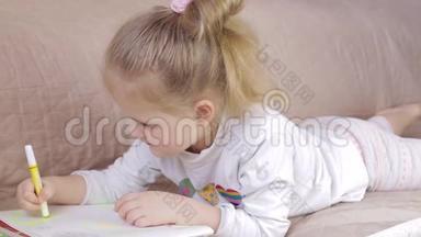 年轻女孩躺在沙发上画画。 女孩在家画画