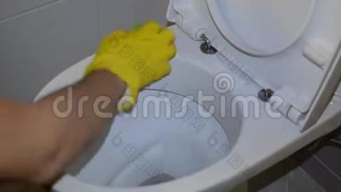 一名家庭佣工用黄色手套中的家用化学品清洁厕所
