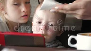 可爱的小男孩坐在咖啡馆里，和父母通电话看动画片。