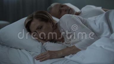 一对老夫妇<strong>躺在床上</strong>醒着，女人把她背对着<strong>男人</strong>，怨恨