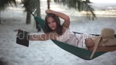 放松的漂亮女孩与手机<strong>销售</strong>手机自拍躺在吊床之间的棕榈树。 1920x1080