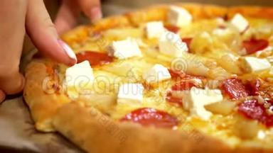 特写美味的披萨摆在桌子上，而双手正在分离美味的切片，上面有奶酪和肉，快餐