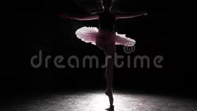 黑色混凝土地板背景下尖角鞋上年轻芭蕾舞者的美丽轮廓。 芭蕾舞练习。 美丽美丽