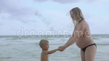 年轻的怀<strong>孕妈妈</strong>和她的儿子在海滩上玩和玩