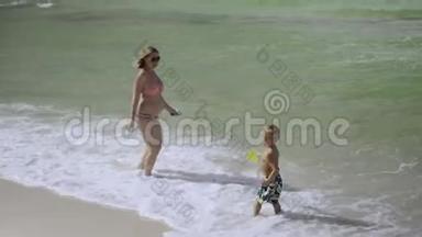 年轻的怀孕妈妈和她的儿子在海滩上玩和玩