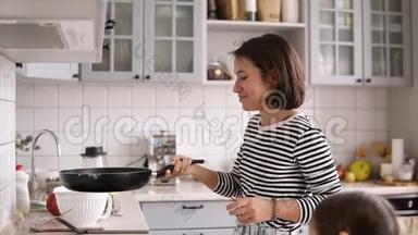 一位<strong>棕色短发</strong>的美女在煎锅里翻着煎饼，微笑着