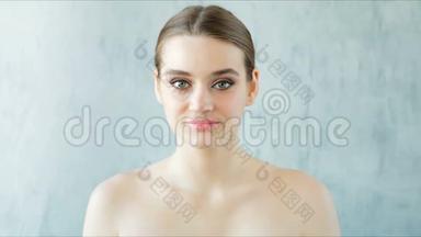 美丽的年轻女人，完美的新鲜皮肤看着相机。 护肤概念