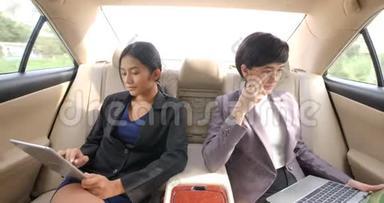 <strong>两个</strong>年轻的女商人在一辆车的后座上放着平板<strong>电脑</strong>和笔记本<strong>电脑</strong>