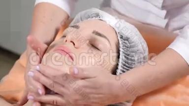 美的概念。 关闭美容师做面部按摩，准备客户面部皮肤注射肉毒杆菌。 面部