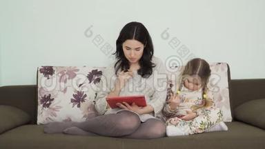 母亲使用数码平板电脑，女儿则使用沙发上的智能手机