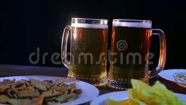 酒保在桌子上放着黑色背景上的零食，<strong>两杯</strong>满是泡沫的<strong>啤酒</strong>