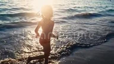 一个赤脚的小女孩在晚阳的温<strong>暖</strong>光线下沿着大海在潮湿的沙子上奔跑的缓慢运动。 粗<strong>心</strong>和粗<strong>心</strong>