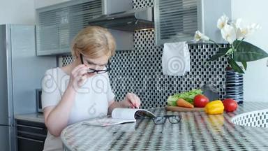 女人坐在餐桌旁的厨房里，正在看一道菜的<strong>菜谱</strong>