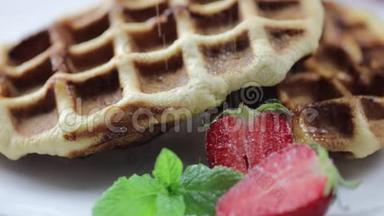 比利时华夫饼，盘子里有新鲜草莓。 厨师`手洒甜点糖粉