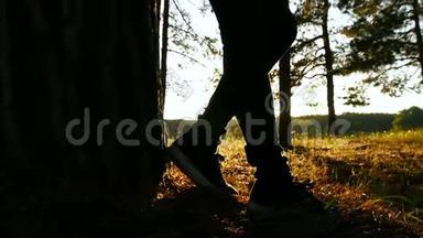 日落时，一个年轻的女孩正站在森林里，背对着树。 树林里一个女孩的剪影。