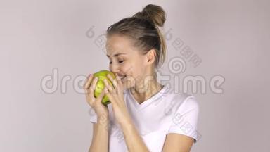 <strong>漂亮</strong>的年轻女孩咬了一个<strong>大绿</strong>苹果。 她抬起拇指微笑着