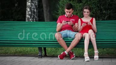 年轻人在公园里玩手机游戏。 在街上，人们经过。 他们手里拿着智能手机。