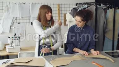 有经验的裁缝正在教年轻女人缝制袖子。 她在说话，打手势，展示纺织品和服装