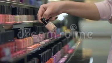 采购女孩选择指甲油美甲和修脚从大量瓶指甲油在商店橱窗