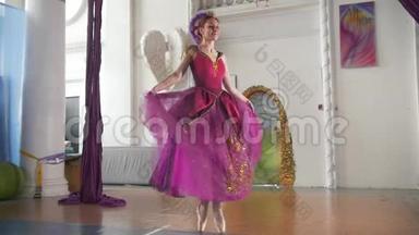 年轻漂亮的穿着紫色衣服的芭蕾舞女演员在宽敞的白色工作室里表演舞蹈