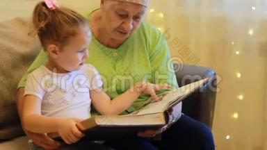 外婆和孙女一起读童话书.. 祖母拥抱她的孙女。