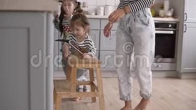 年轻时尚的母亲帮助女儿用铲子翻煎饼，在厨房一起做饭时玩得很开心。
