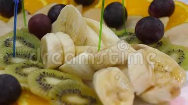巴奈，橘子，葡萄，奇异果切片，特写.. 节日餐桌上的新鲜水果盘。 各种切片水果串