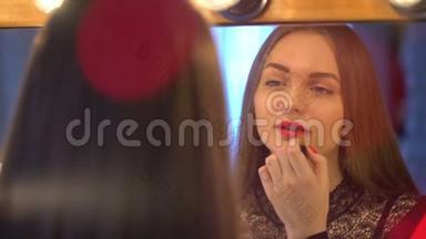 一个年轻漂亮的女人正在化妆，照镜子，一个女人在涂红唇膏